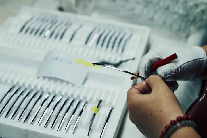 Trays of steel temple components under inspection before assembly