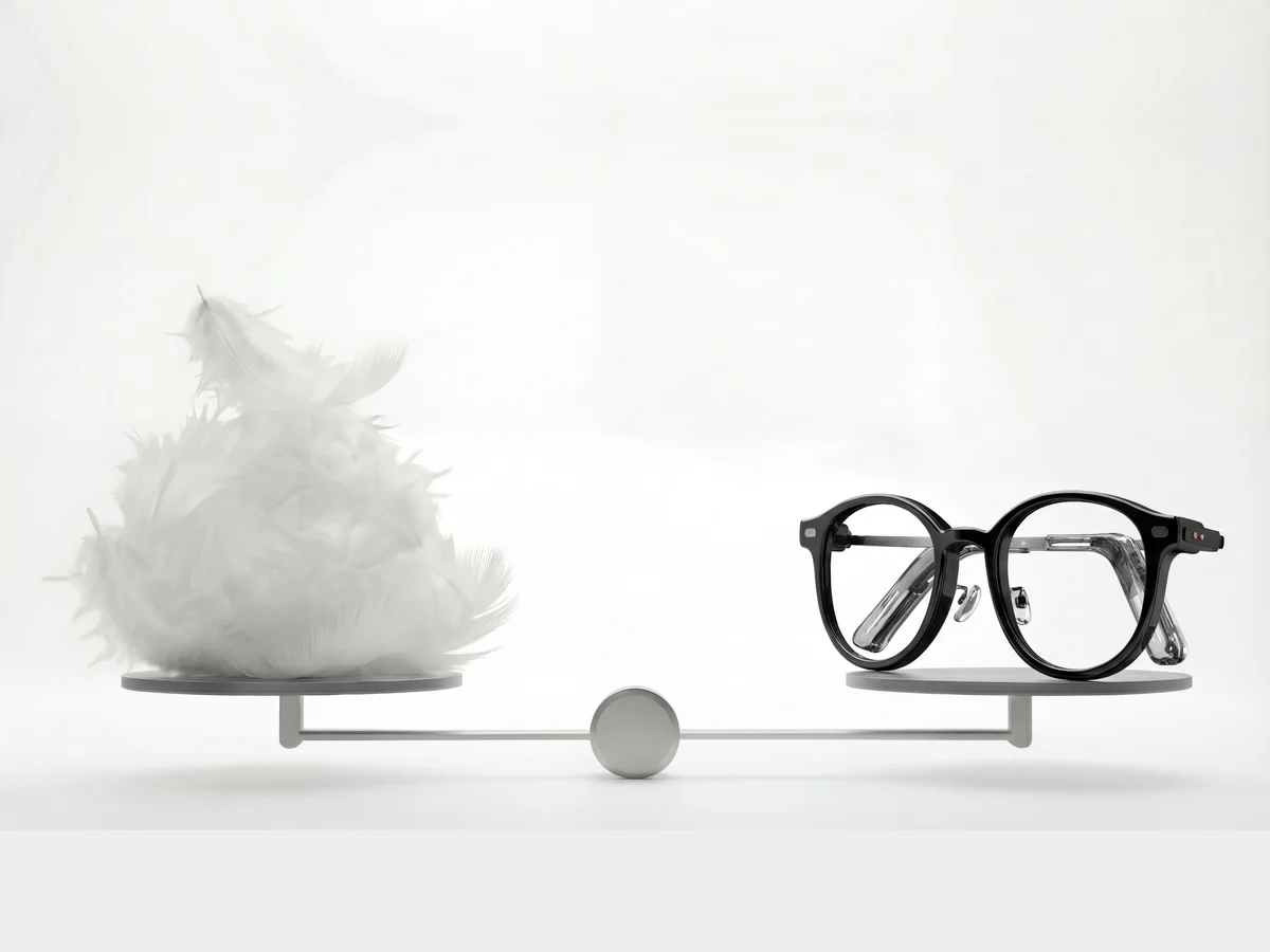The NIMO frame on one pan of a balance, a mound of white feathers on the other, resting level